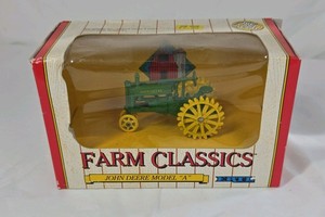Diecast John Deere Model A tractor features a green body with yellow spoked wheels and detailed engine components. Packaged in the original window box labeled Farm Classics by ERTL. Classic farm toy replica design.