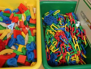 GREEN AND YELLOW TOTES FULL OF COLORFUL TOYSCHAIN LINK TOY