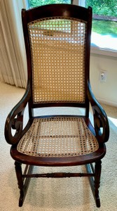 Vintage rocking chair cherry wood framed, light colored woven cane back and seat