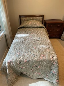 Vintage French Provincial style twin bed, dark wood frame with a cushioned, light green floral upholstered headboard