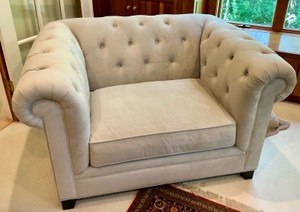 Cream colored velvet armchair with deep-button tufting and rolled arms