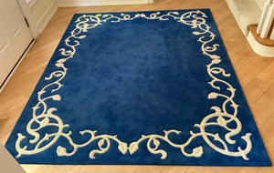 Blue area rug with distinctive cream-colored floral border pattern