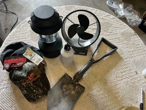 Coleman lantern, a battery-operated fan, a shovel, a water bottle, and a camouflage hat