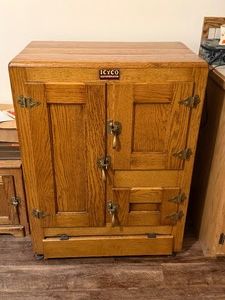 antique oak icebox, a precursor to the modern electric refrigerator popular from the late 19th century through the 1920s. The specific brand tag visible on the front identifies it as an Icyco Refrigerator - BRING HELP TO LOAD