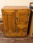 antique oak icebox, a precursor to the modern electric refrigerator popular from the late 19th century through the 1920s. The specific brand tag visible on the front identifies it as an Icyco Refrigerator - BRING HELP TO LOAD