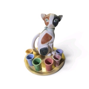 Vintage ceramic cat set, includes a centerpiece cat figurine and six small, colorful cups on a matching round tray.