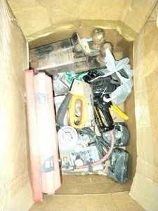 This box contains a variety of mixed garage and shop tools, including a red plastic case and a staple gun.