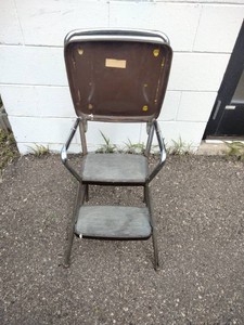 This is a vintage Mid-Century Modern Cosco kitchen step stool featuring a brown flip-up seat and chrome frame.