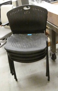 Four black plastic stacking chairs