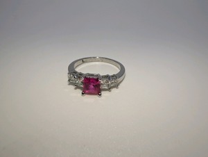 Plated central pink princess-cut stone flanked by smaller square-cut clear stones ring, size 6