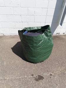 Heavy-duty, reusable garden waste bag full of moving blankets and tarps