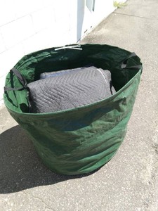 Heavy-duty, reusable garden waste bag full of moving blankets and tarps