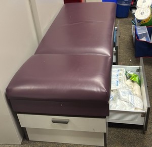 purple medical bed with cabinets, full of stuff
