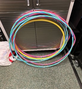Outdoor activities including hoola hoops, gray net bag of wifle balls, frisbees, chalk, jump ropes and more