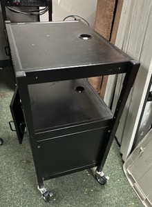 Black metal media cart on wheels with doors.