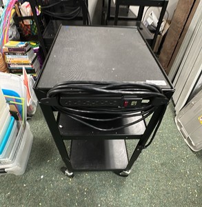 Black metal media cart on wheels with cord and pull out tray.