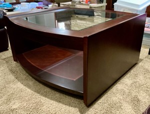 Modern coffee table with deep red, mahogany-toned finish and a curved, tempered glass top