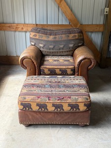 rustic lodge armchair and matching ottoman set featuring a distinctive wildlife theme. The upholstery showcases a prominent bear and elk motif tapestry combined with distressed brown faux leather or microfiber arms and base