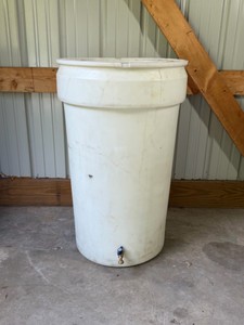 molded polyethylene water storage container or rain barrel fitted with a brass spigot at the bottom.