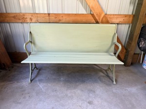 vintage cast iron and wood garden bench painted in a light sage or pistachio green finish