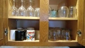 cupboard full of mugs, wine glasses and cocktail glasses including Woody Wood Pecker and other advertisements