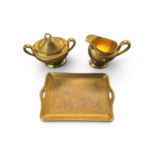 This gold-encrusted creamer, sugar bowl, and tray set was produced by Porzellanfabrik Moschendorf in Bavaria, Germany. This specific company used the backstamp associated with such pieces between 1910 and 1957.