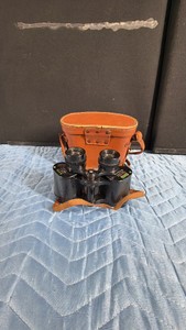 vintage pair of Olympia Deluxe Prismatic 8x30 wide-angle binoculars complete with its original brown leather carrying case.