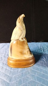 Hand-carved eagle sculpture made from water buffalo horn mounted on a wooden base