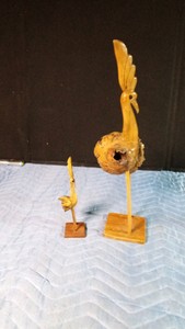 Handcrafted folk art peacock sculpture made from natural burl wood, often utilizing the natural knot formation of the wood for the body