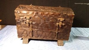 Vintage carved wooden chest with iron hinges with chain closures secured with metal straps and has handles