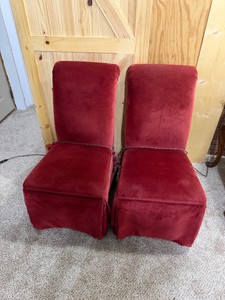 French Napoleon III-style slipper chairs (also commonly referred to as boudoir or nursing chairs) that have been fitted with floor-length red velvet slipcovers and accented with decorative corded tassels