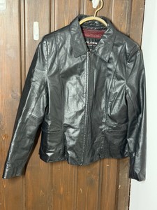 Vintage Wilsons Leather black zip-up jacket featuring a prominent burgundyred quilted interior lining. This minimalist, classic collared style is typical of the brands popular designs from the 1990s and early 2000s.