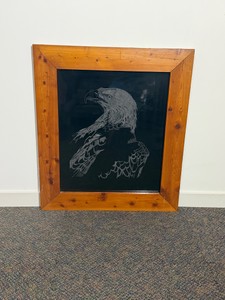 Piece of bald eagle wall art depicted on a dark, reflective surface encased in a thick, rustic wooden frame.