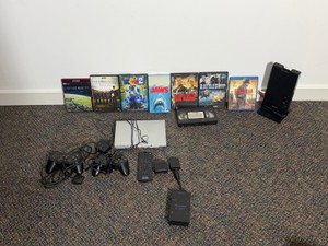 Sony PlayStation 2, 2- Sony PlayStation Controllers, Sony Surround Sound Processor for Compatible Headphones, PlayStation 2 Remote, Sony Wireless Control Receiver, Sony PlayStation 2 Multi Tap Adaptor, DVDs, Jaws VHS (Still wrapped in Plastic)