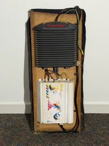 Vintage Rockford Fosgate car audio setup mounted on a wooden amp rack, featuring an older black finned Punch amplifier stacked above a white graphic equalizer or secondary unit.