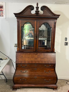 Vintage drop-front secretary desk with a bookcase hutch, featuring a distinctive double-bonnet or broken-pediment top with a central finial. High-end furniture brands such as Henredon Furniture, Thomasville, and Ethan Allen famously produced these traditi