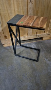modern industrial C-table features a distinctive split top with natural wood on one side and a dark stone finish on the other, supported by a sturdy black metal frame.