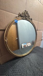 antique French Rococo style oval mirror featuring an ornate gold gilt frame