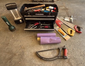 husky toolbox with miscellaneous tools, saws, and flashlights