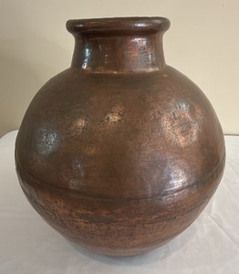 This vintage hand-hammered copper water vessel showcases a classic rounded body and warm, aged metallic patina