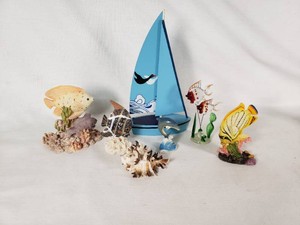 Collection of marine-themed figurines including fish, dolphin, sailboat, and coral