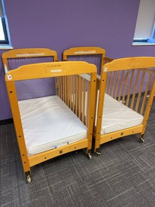 Pair of Compact Wooden Window Crib features clear acrylic panels at both ends for high visibility. Wooden Daycare Baby Cribs With Mattresses on Casters. Each Retails for $375