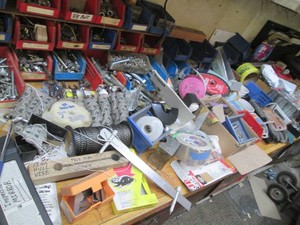 Massive supply of assorted hardware, nuts, bolts, screws and more plus organizer bins and other supplies shown on benchtop