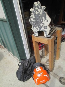 Spring loaded target practice device on wood bade with protective helmet for head and ears