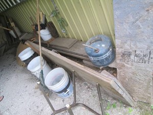 Large amount of lumber planks and sections, misc pieces and assorted plywood along wall and parameter of lean-to