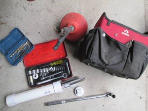 Husky top handle open top toolbag with various tools and accessories plus a ridgid manual drain auger