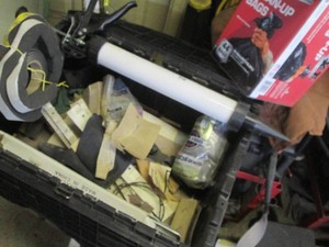 Clamshell closing tote containing sanding supplies and foam door seal insulation, contractor clean up bags and caulking gun