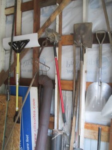 Scoop and assorted shovels, tamper, post hole digger, rakes, masonry levelers and other items shown