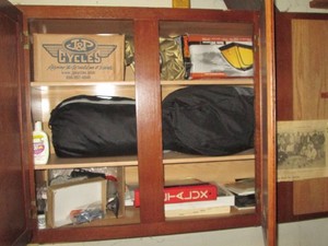 Content of garage cupboard to include a camping tent and supplies, automotive replacement bulbs and other items shown