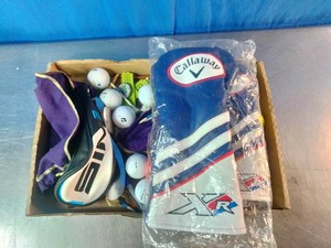 A mix of golf gear, primarily featuring branded golf club headcovers and loose accessories.